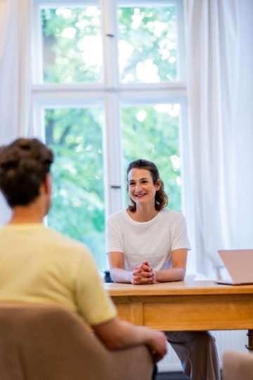 Person im Gespräch vor Fenster.